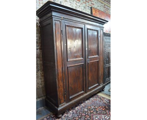 A substantial 18th century Palazzo scale Florentine fruitwood armoire, the dentil moulded canopy top over twin panelled doors