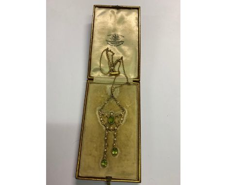A yellow gold Art Nouveau peridot and pearl pendant, the central oval peridot with seed pearl wings on either side and with t