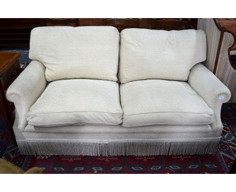 George Smith Ltd., a contemporary two seater sofa upholstered in oatmeal chenille fabric with all-round tasselled base obscur