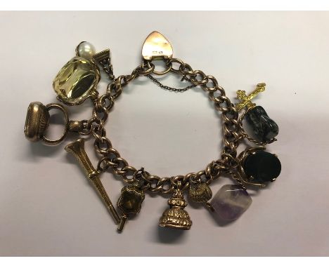 A 9ct rose gold curb bracelet with padlock and safety chain, with twelve various charms attached including citrine swivel, bl