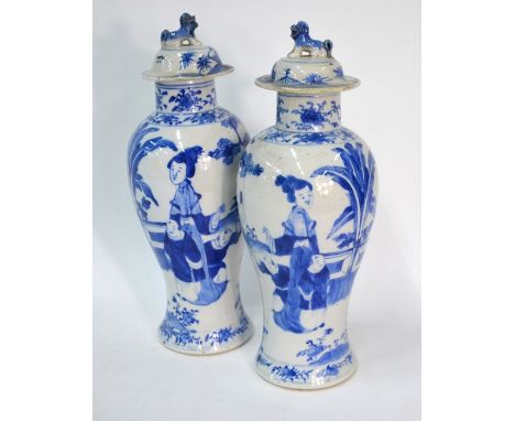 A pair of Chinese blue and white baluster vases; each one with an associated domed cover and decorated with Manchu/Chinese fi