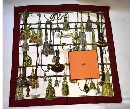 A boxed Hermes Passementerie (trimmings) silk scarf designed by Francoise Heron in 1960, deep red border with hanging tassels