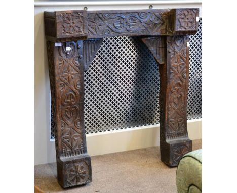 A Carved Oak Fire Surround, in three sections, carved overall with C scrolls and flowerheads, the mantel of inverted breakfro