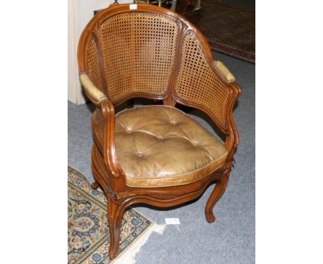A Late 19th/Early 20th Century Walnut Framed Bergère, with caned back support and seat, upholstered in green close-nailed lea