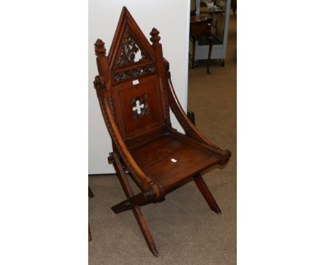 A Victorian Gothic Revival Cross Frame Chair, late 19th century, with a fret carved architectural pediment above a panelled b