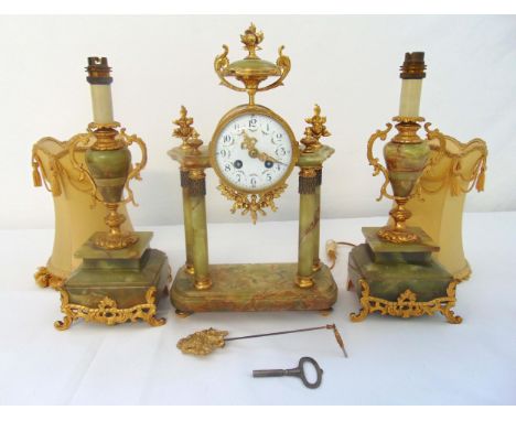A late 19th century French onyx and gilt metal clock set flanked by lamp garnitures on raised square bases, to include pendul