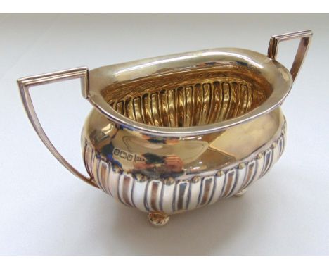 A hallmarked silver sugar bowl part fluted with angled handle on four bun feet Sheffield 1933 by Walker and Hall, approx tota