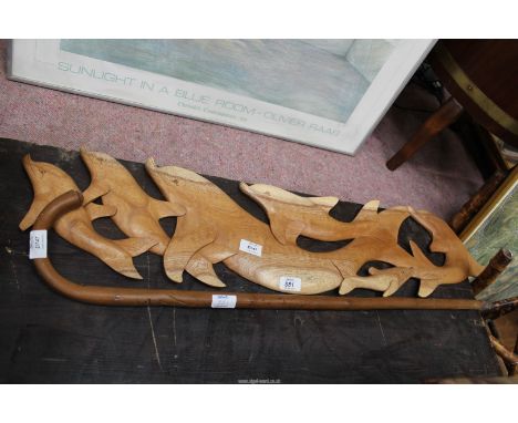 A wall plaque of dolphins and a wooden walking stick.