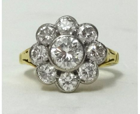 A fine diamond cluster ring in 18ct gold, consisting of eight diamonds surrounding a large centre diamond within a milligrain