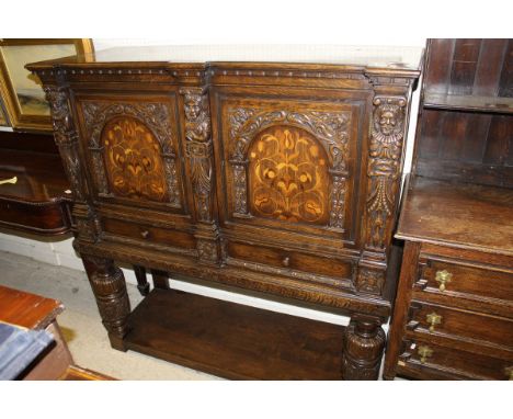 A 20th Century oak cupboard in the 17th Century manner, the plain top above two marquetry inlaid panel doors with carved arch