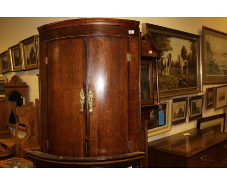 A 19th Century oak and mahogany banded bow front wall hanging corner cupboard of two doors enclosing shelves