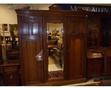 An Edwardian mahogany bedroom suite to include three door wardrobe with architectural pediment above a mirrored central door 