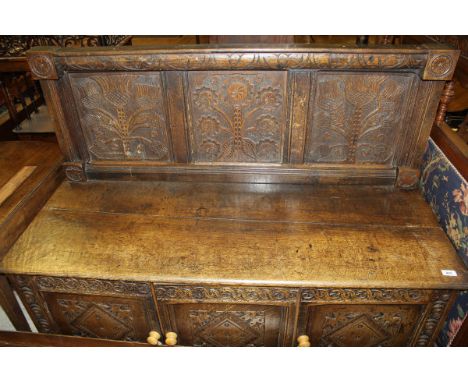 A 19th Century oak bench, the panelled back carved with flowers, above a plain seat and base of three diamond carved cupboard