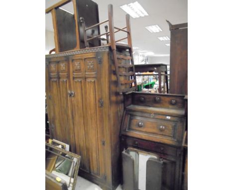 A 20th Century two door wardrobe with carved pediment above the two doors with applied linen fold moulding, raised on bracket