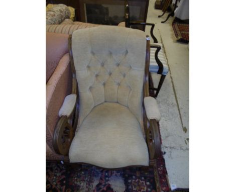 A mahogany framed armchair in pale gold button back upholstery, with shaped front rail, raised on turned legs to brass caps a