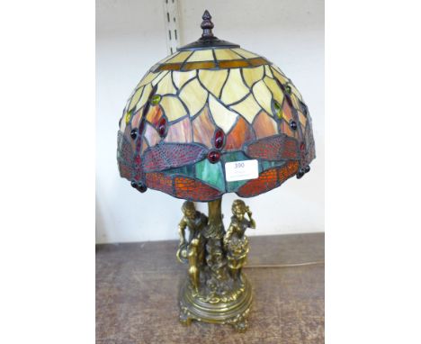 A figural table lamp with Tiffany style shade