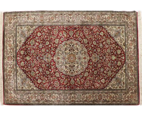 A pair of Persian silk rugs, late 20th century, Kashan, each field woven with dense scrolling floral and foliate motifs, on a