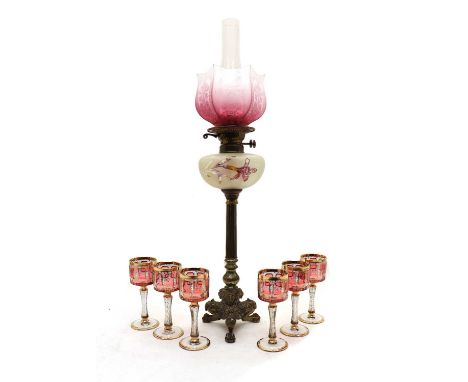 A Victorian brass oil lamp, the cranberry glass etched shade with opaque glass reservoir raised on a brass column and triform