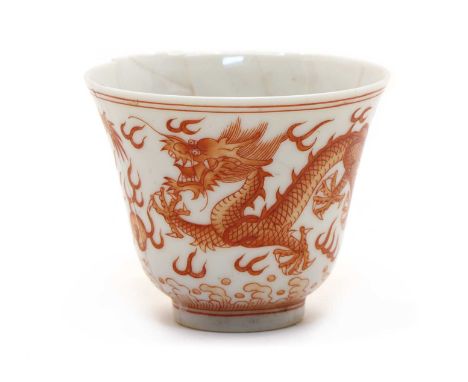 A Chinese iron-red cup, of tapering form, painted with dragons chasing a flaming pearl above spuming waves, six-character Ton