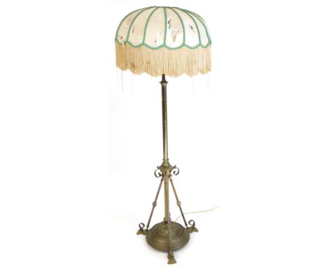 An early 20thC brass standard lamp, with a tasselled silk shade, 145cm high. (AF) Buyer Note: WARNING! This lot contains unte
