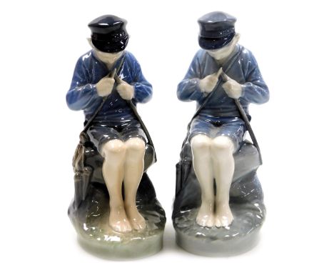 A pair of Royal Copenhagen porcelain figures of a boy, modelled seated whittling a stick, no. 905, printed and painted marks,