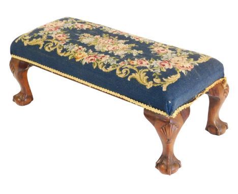 A Georgian style mahogany double stool, upholstered in rose pattern wool work tapestry, raised on four leaf capped cabriole l