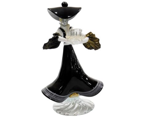 A Murano glass candlestick, of a figure of a lady wearing a black and white striped frilled dress, oversized hat, and puffed 