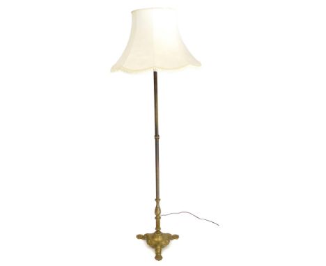An early 20thC brass standard lamp, with a cream shade, 177cm high.