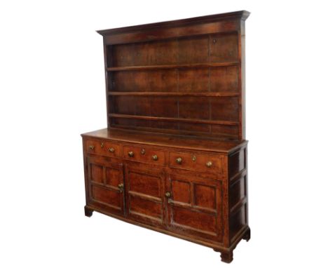 A Georgian oak dresser, the outswept pediment over a shallow three shelf plate rack, above three frieze drawers over three pa