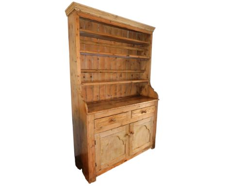 A Victorian pine kitchen dresser, the pediment over three shelves, the middle and bottom shelf with plate supports, over two 