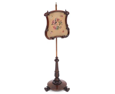 A Victorian rosewood pole screen, the shield shaped screen with wool work floral tapestry, raised on a lappet carved column a