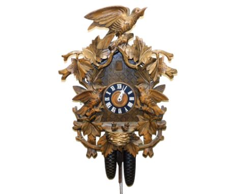 A Black Forest cuckoo clock, circular dial bearing Roman numerals, two train movement, the case profusely carved to the front