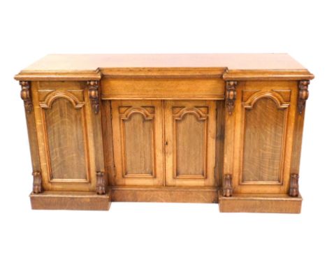 A Victorian oak breakfront sideboard, with a central cushioned drawer, over a pair of cupboard doors, enclosing a single shel