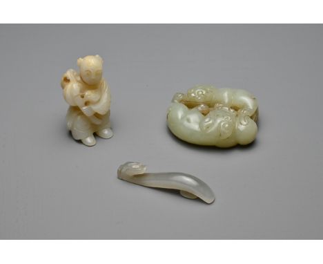 THREE CHINESE CARVED JADE ITEMS. To include a celadon lion group; A small grey dragon head belt hook; Together with a figure 