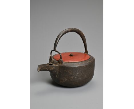 A 20TH CENTURY JAPANESE CAST IRON CHOSHI (SAKE EWER), set on tripod feet with red lacquered wood cover and cast decorations o