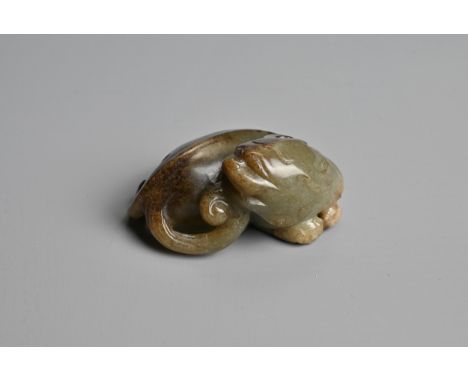 A CHINESE CELADON AND BROWN JADE CARVING OF A BUDDHIST LION, QING DYNASTY. The nephrite jade figure of a lion recumbent with 