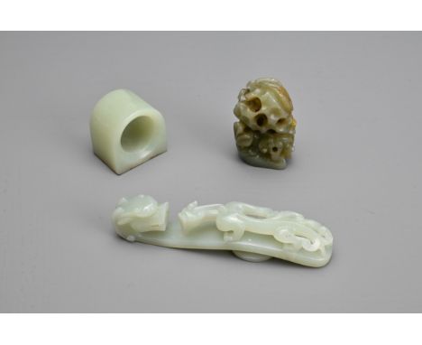 THREE CHINESE CARVED JADE ITEMS. To include pale celadon openwork chilong and dragon head belt hook; A thumb ring; Together w