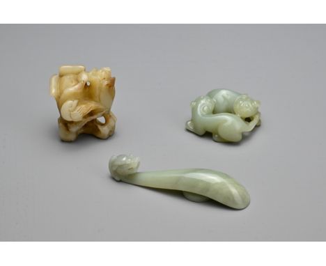THREE CHINESE CARVED JADE ITEMS. To include a celadon lion cub group; A celadon dragon head belt hook; Together with a browni