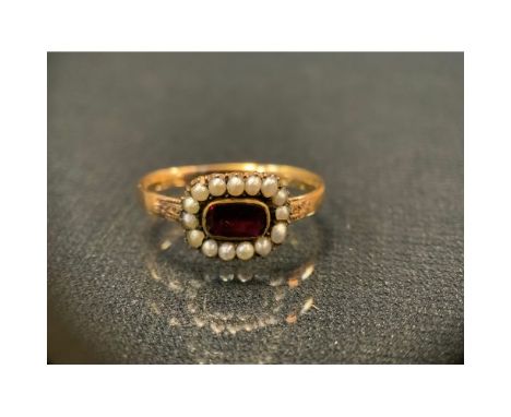 A 19th century garnet and seed pearl mourning ring, unmarked yellow metal shank, size T, 3.7g gross
