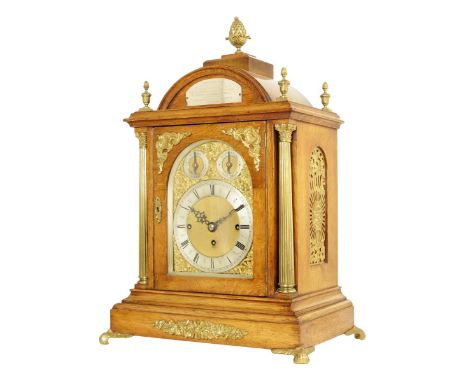 An oak quarter chiming mantel clock, the 7 inch brass dial with silvered chapter ring and matted centre, the arch containing 