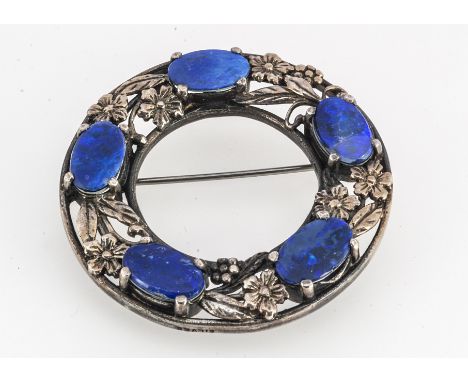 A black opal doublet and silver wreath brooch, in the Arts and Crafts style, the five oval opals claw set, on a pierced flora