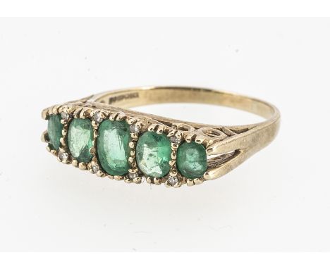 An emerald and diamond chip five stone dress ring, the oval graduated cuts, alternately set with diamond chips, largest centr