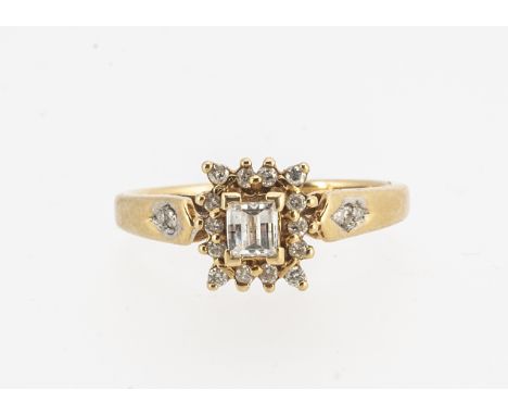 A modern 18ct gold diamond set cluster ring,  comprising a faceted claw set diamond, surrounded by small brilliant cuts in ye
