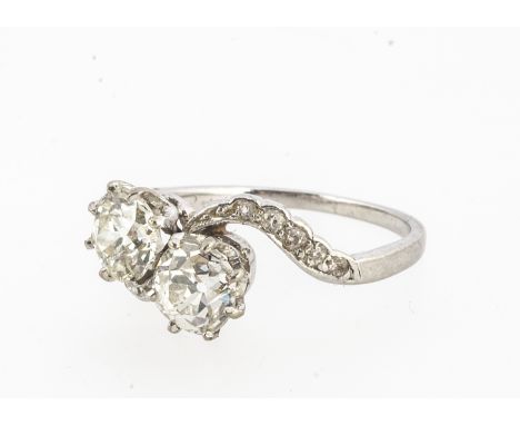 A white metal diamond cross over ring, the old cuts in claw settings, with diamond set shoulders, diamonds 0.75cts and 0.66ct