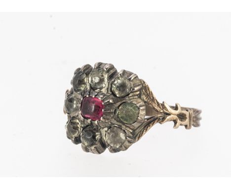 A 19th century paste set cluster ring, centred with a red paste stone surrounded by colourless examples, on shaped pierced fe