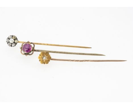 An Edwardian 15ct marked flower head stick pin with a central old cut diamond, 5.8 cm long, together with a synthetic ruby ex