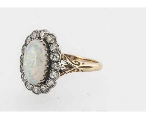 An early 20th century white precious opal and diamond cluster ring, the oval cabochon, claw set, surrounded by old cut diamon