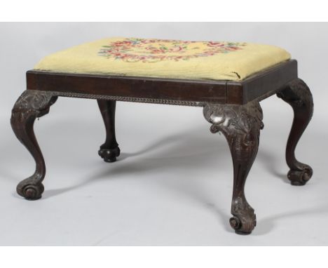 A Victorian George II style carved wood footstool, with floral tapestry seat above gadrooned apron, supported on four acanthu