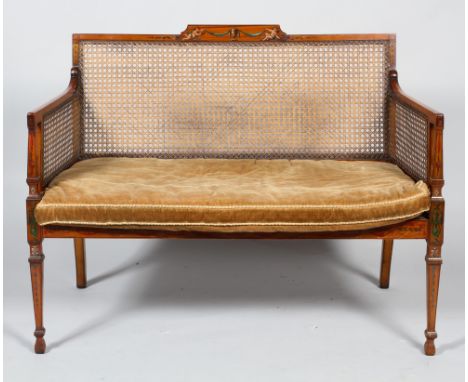 An Edwardian painted mahogany two seater Bergere sofa, the top rail with central painted panel of two putti with caned seat a