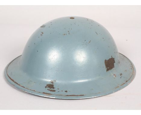 A Brodie steel Civil Defence helmet, with leather lining and canvas strap, over-painted in grey-blue, the interior fitting 17